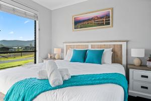 a bedroom with a large bed with blue pillows at Luxury Hunter Valley Acreage - Heated SwimSpa - Mountain Views - Pool Table - Fire Pitt in Millfield