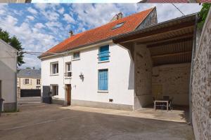 ein großes weißes Haus mit einem Stuhl davor in der Unterkunft Maison indépendante proche Paris Saclay, Massy in La Ville-du-Bois