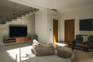 a living room with a couch and a television at Large 6BR Tulum Villa with Pool Aldea Zama in Tulum