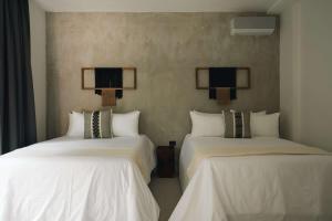 two beds in a hotel room with white sheets at Large 6BR Tulum Villa with Pool Aldea Zama in Tulum