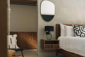 a bedroom with a bed with a mirror and a chair at Large 6BR Tulum Villa with Pool Aldea Zama in Tulum +30 photos