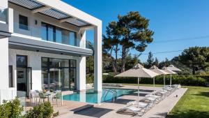 a villa with a swimming pool with chairs and umbrellas at Armonia Luxury Villa in Triánta
