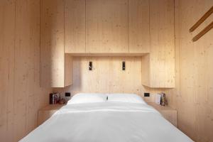 a bedroom with a white bed with wooden walls at Cervino loft in Breuil-Cervinia