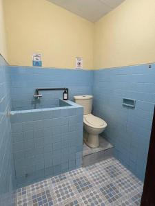 a bathroom with a toilet and a blue tile wall at Dehome Pakuwon Mall 2 Syariah in Surabaya