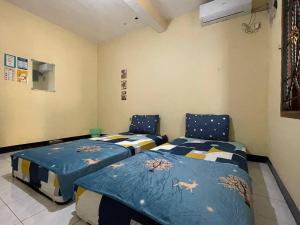 a bedroom with two beds with blue comforters at Dehome Pakuwon Mall 2 Syariah in Surabaya