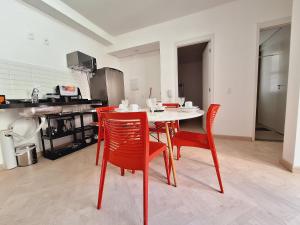 a kitchen with a white table and red chairs at LK Centro 2 in Belo Horizonte +33 photos