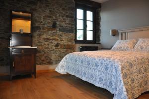 una camera con letto e parete in pietra di Casa Pacho Apartamentos Rurales a Luarca