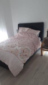 - un lit avec une couette et des oreillers roses et blancs dans l'établissement birsinger, à Bobigny