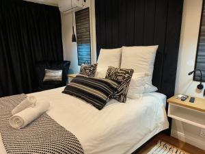 a bed with black and white pillows on it at Bel-Air Guesthouse in Klerksdorp