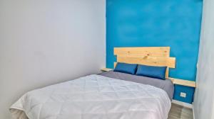 una camera da letto con un letto con una parete blu di Le Grain de Sable a Cap d'Agde