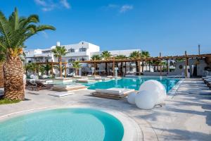 卡马利Smy Mediterranean White Santorini的一座带躺椅和棕榈树的度假村的游泳池