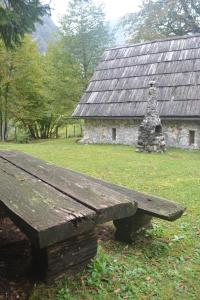 un banc en bois assis devant un bâtiment en pierre dans l'établissement House Pod Lipo, à Trenta