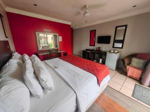 a bedroom with a large bed with a red wall at Leondale Guest House in Germiston