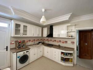a kitchen with white cabinets and a washer and dryer at Dar Sammoud A1 in Kelibia