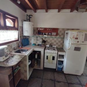 a small kitchen with a white refrigerator and a sink at Cabañas Lycas II in El Bolsón