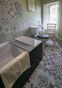 a bathroom with a bath tub and a toilet at Beautiful Lodge Cottage near Belvoir Castle in Lincolnshire +19 photos