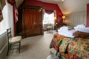 a bedroom with two beds with red walls and a dresser at Beautiful Lodge Cottage near Belvoir Castle in Lincolnshire