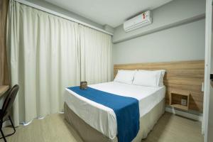 圣保罗Apartamentos Studio Allure Moema - Com café da manhã opcional, Recepção e Valet 24 horas的卧室里有一张床，床上铺着蓝白相间的毯子