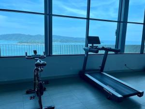 a gym with a treadmill and a bike in a room with windows at Cozy JQ Level 25 Full Sea&Sunset View in Kota Kinabalu