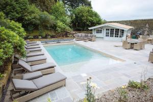a swimming pool with lounge chairs and a patio at Moscar Lodge, Peak District in Ughill