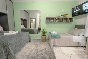 a bedroom with two beds and a flat screen tv at Lar Estilo e Conforto - RJ2-19 in Maringá