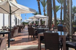 a restaurant with tables and umbrellas and palm trees at Hacienda Apartment in Sucina