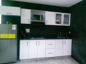 a kitchen with white cabinets and a refrigerator at Hotel Septima Avenida in Neiva