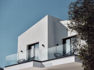 a white house with glass balconies and a tree at Estelle Villa, a Flamboyant Escape with Pool, By ThinkVilla in Zakynthos Town