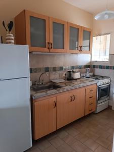 een keuken met houten kasten en een witte koelkast bij Santa Ana Alojamiento in Puerto Madryn