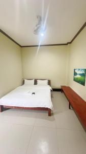 a bedroom with a white bed and a bench at Happy Hotel in Vang Vieng