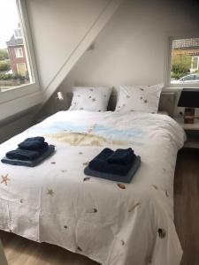 a bedroom with a white bed with towels on it at Hello Noordwijk - Familiehuis Quarles van Uffordstraat 77 in Noordwijk aan Zee