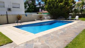 a swimming pool in a yard with chairs around it at Oceana Suites Remanso in Punta del Este
