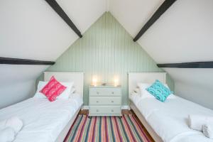 2 Betten in einem Dachzimmer mit weißen und farbenfrohen Kissen in der Unterkunft Bwthyn Beatties in Haverfordwest
