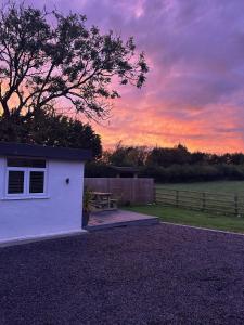 a white shed with a sunset in the background at Seiriol, Modern Lodge with Games Room Access in Menai Bridge