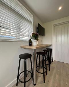 a kitchen with a bar with stools and a counter at Seiriol, Modern Lodge with Games Room Access in Menai Bridge +21 photos