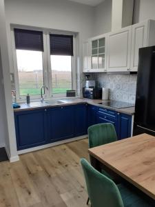 a kitchen with blue cabinets and a table with chairs at Sarenkowo dom z balia ogrodowa in Pokrzywnica