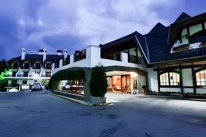 Un gran edificio con un coche aparcado delante. en Apartamento Rosa en Castelo para Familia, en Campos do Jordão