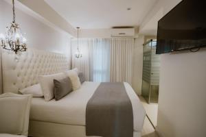 a bedroom with a large white bed and a television at Hotel Club del Golf in Mar del Plata