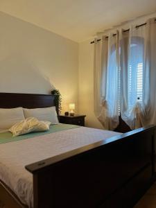 a bedroom with a bed with white sheets and a window at Casetta immersa nel verde, lontano dal caos in Lampedusa
