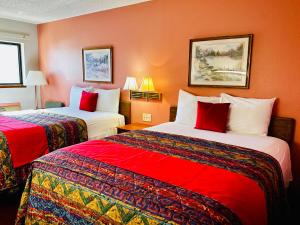 two beds in a hotel room with red walls at American Inn Ozark in Ozark