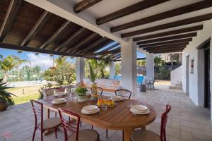 a wooden table and chairs on a patio at Villa a 300 Mt. dal Mare (Magaggiari) con campo da tennis in Cinisi