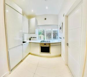 a kitchen with white cabinets and a large window at Family flat in Camden, top location, next to attractions in London