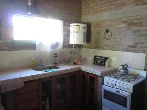a kitchen with a sink and a stove and a window at El Campito casa frente al río in Villa Carlos Paz