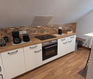 a kitchen with white cabinets and a stove top oven at Ferienwohnung im Erzgebirge - Seiffen in Neuhausen +11 photos