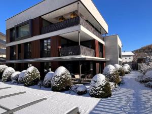 a building with snow covered bushes in front of it at ANTON Dolomites Hideaway in Brunico