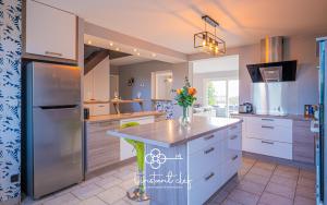 a kitchen with white cabinets and a stainless steel refrigerator at Cœur de Sarthe - Maison 20pers - Balnéo - BBQ in Parigné-lʼÉvêque
