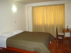 een slaapkamer met een bed, een bureau en een raam bij Kibo Hotel in Ayacucho