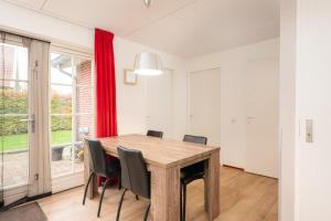 a dining room with a wooden table and chairs at Buitengoed het Lageveld 137 in Hoge-Hexel