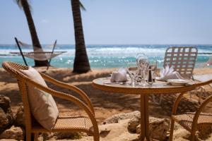 a table and chairs on a beach with the ocean at Sugar Bay Barbados - All Inclusive in Bridgetown
