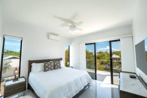 a white bedroom with a bed and a large window at Balfour Villa in Turtle Cove +14 photos
